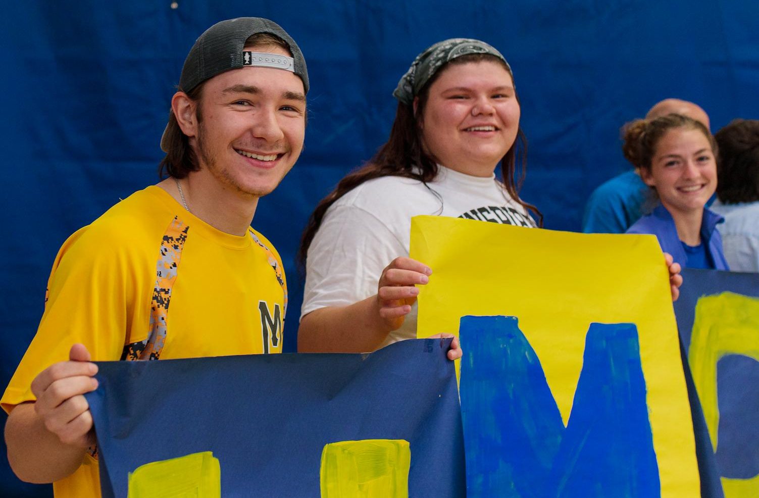 Smiling students at convocation holding up painted posters of UMPI letters