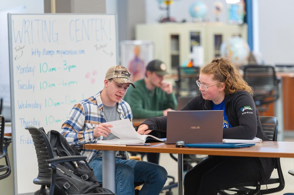 two students sitting at a table doing homework