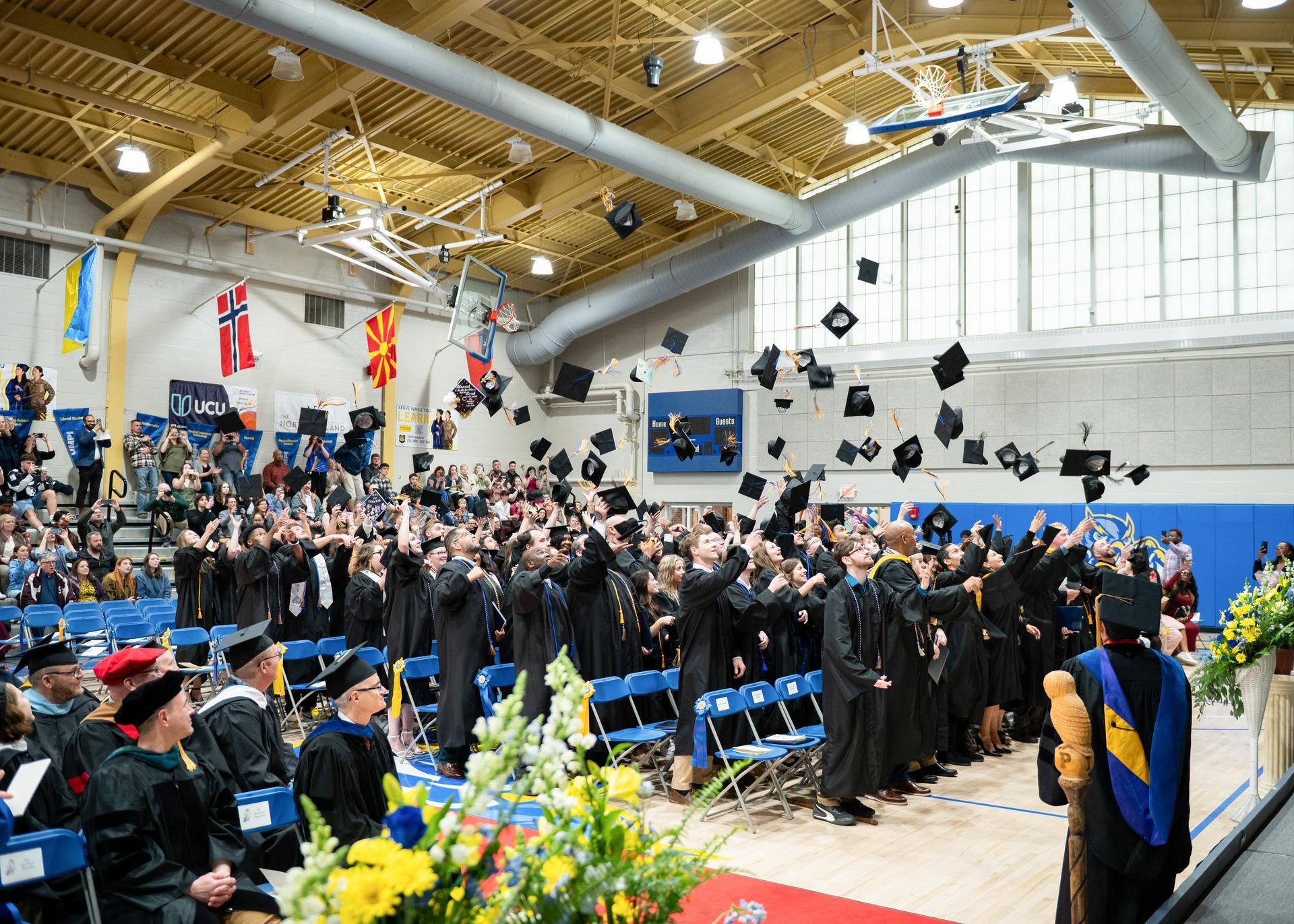 UMPI graduates tossing caps into air.