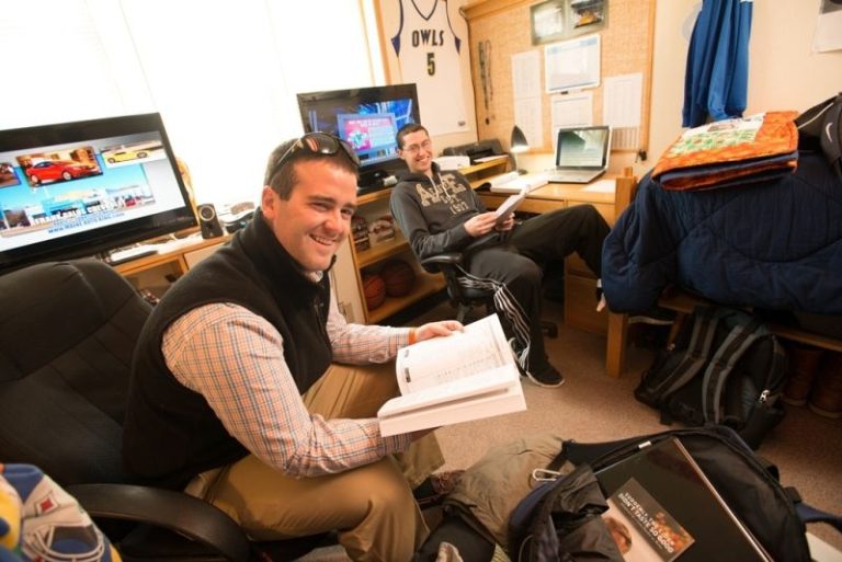Two smiling students in their dorm room