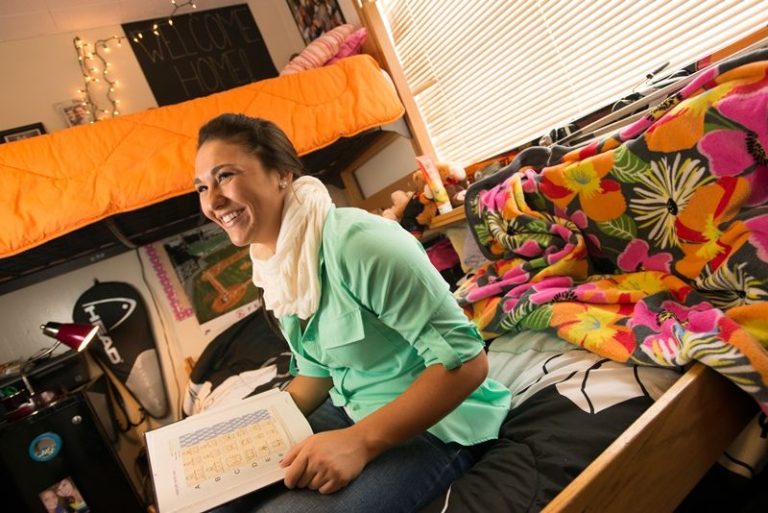 Smiling student studying in their dorm room