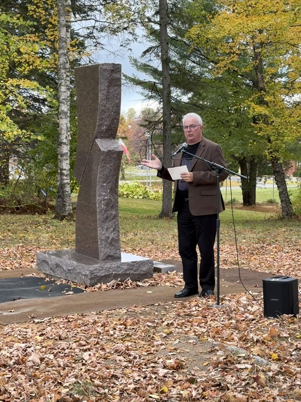 Artist Leo-Paul Cyr standing with the outdoor sculpture "Embrace" at UMPI.